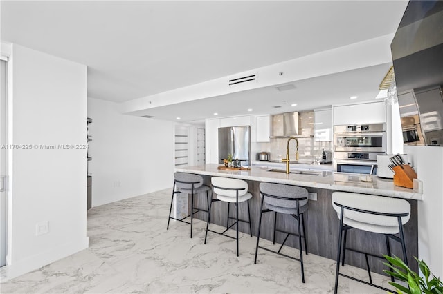 kitchen featuring decorative backsplash, appliances with stainless steel finishes, a kitchen breakfast bar, sink, and white cabinetry