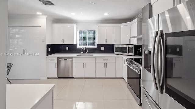 kitchen with sink, light tile patterned floors, decorative backsplash, white cabinets, and appliances with stainless steel finishes