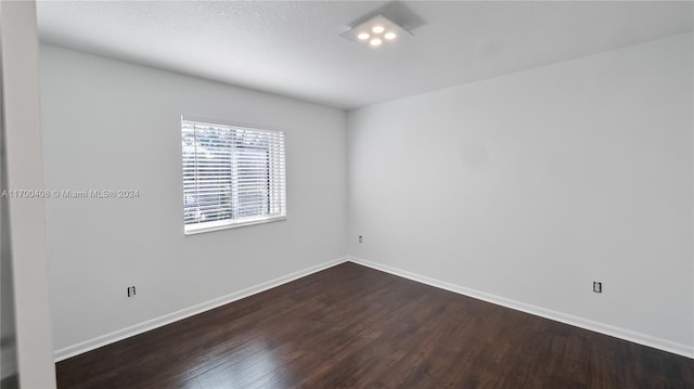 unfurnished room with a textured ceiling and dark wood-type flooring