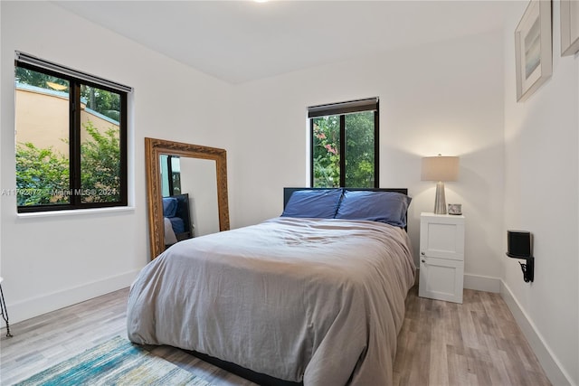 bedroom featuring multiple windows and light hardwood / wood-style flooring