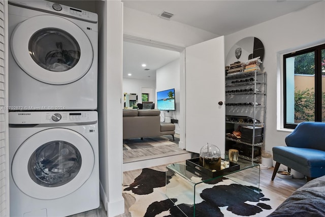 laundry room featuring light hardwood / wood-style floors and stacked washer / dryer