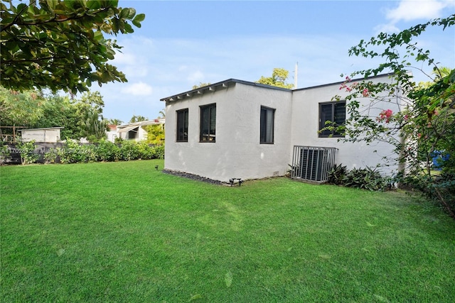 rear view of property with a yard and central AC