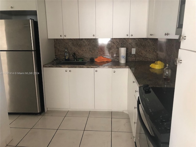 kitchen with stainless steel fridge, black range with electric stovetop, sink, light tile patterned floors, and white cabinetry