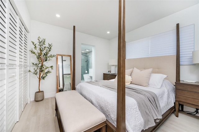 bedroom with connected bathroom and light hardwood / wood-style floors