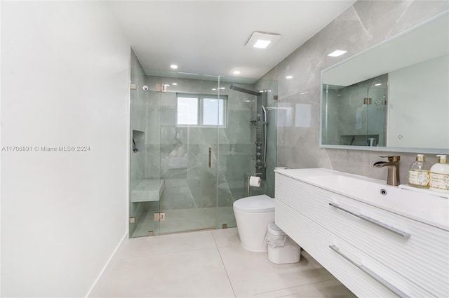 bathroom featuring toilet, vanity, tile patterned floors, and a shower with shower door