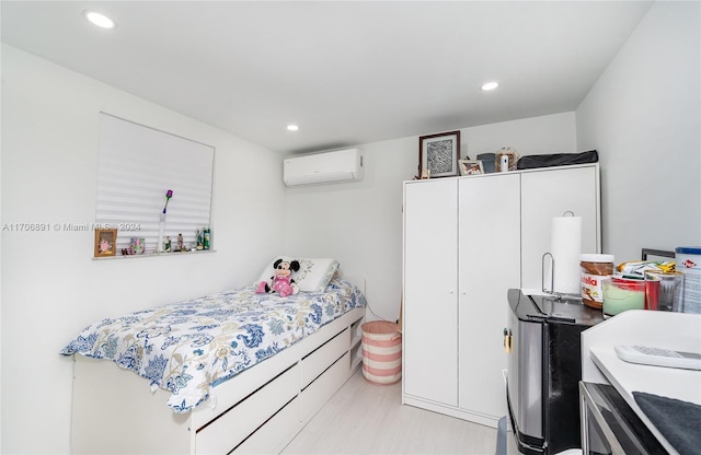 bedroom with a wall unit AC and light hardwood / wood-style floors