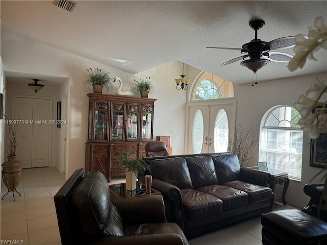 tiled living room with ceiling fan, vaulted ceiling, a textured ceiling, and french doors