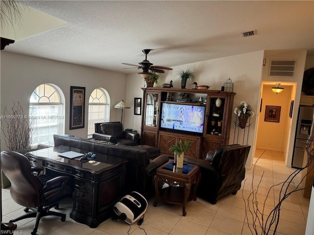 living room featuring ceiling fan, light tile patterned flooring, and a textured ceiling