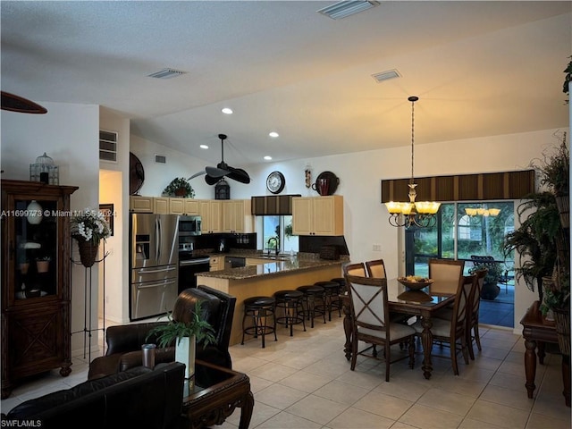 tiled dining area featuring ceiling fan with notable chandelier, lofted ceiling, and sink