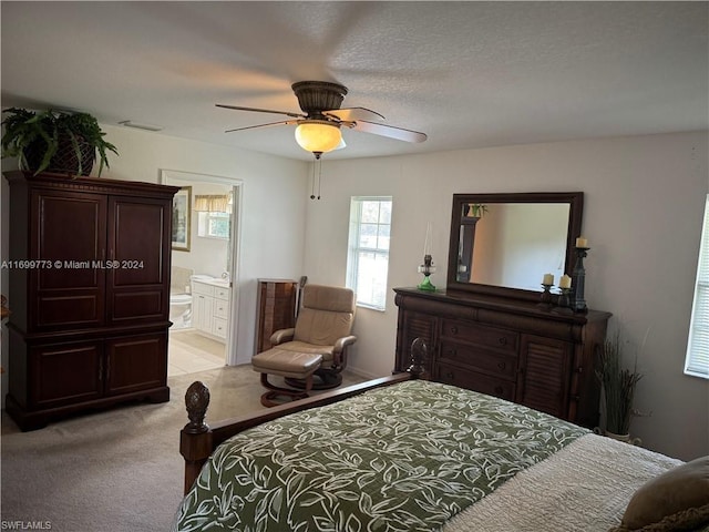 bedroom featuring ensuite bath, ceiling fan, light colored carpet, and a textured ceiling