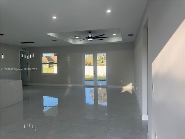 unfurnished room with a tray ceiling, french doors, and ceiling fan