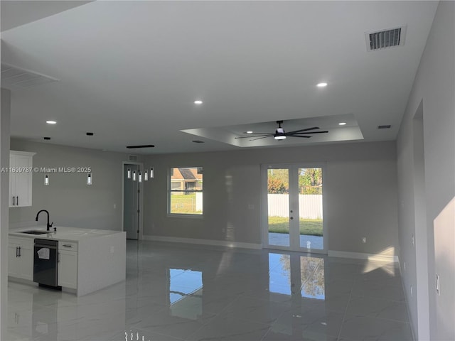 unfurnished room featuring french doors, ceiling fan, a tray ceiling, and sink