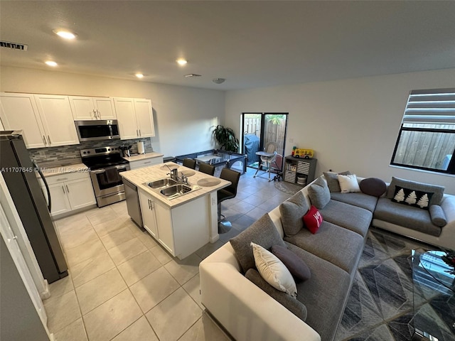 kitchen featuring white cabinets, a healthy amount of sunlight, stainless steel appliances, and a center island with sink