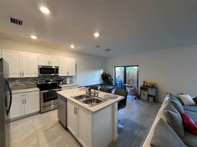 kitchen featuring sink, white cabinets, a center island with sink, light tile patterned floors, and appliances with stainless steel finishes