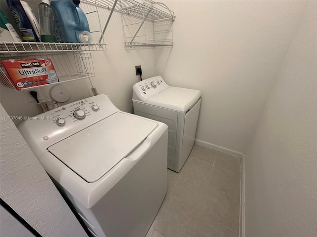 clothes washing area featuring light tile patterned floors and washer and clothes dryer