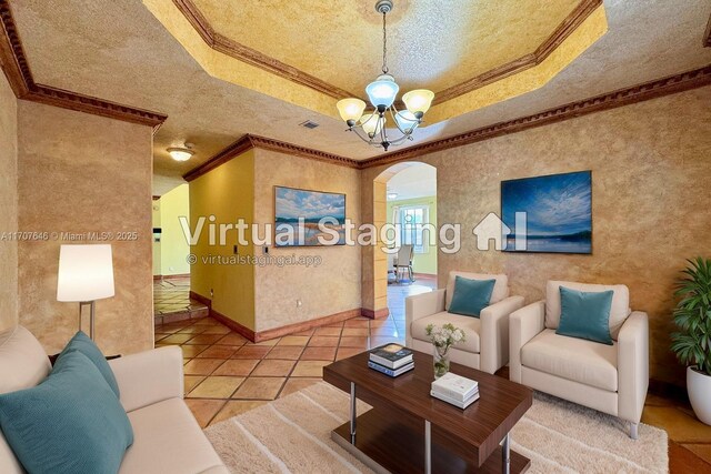 unfurnished room with a raised ceiling, ornamental molding, a textured ceiling, and an inviting chandelier