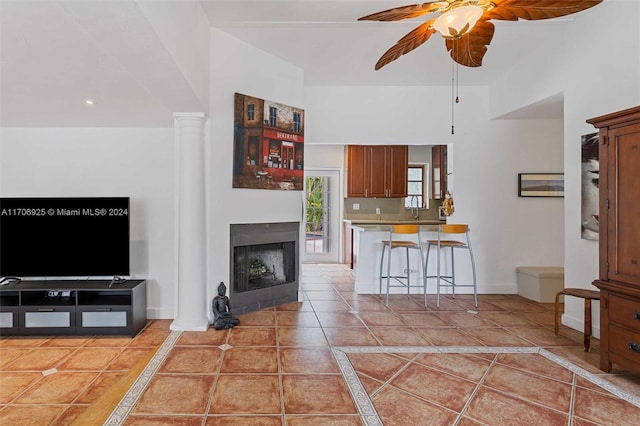 tiled living room with ceiling fan and decorative columns