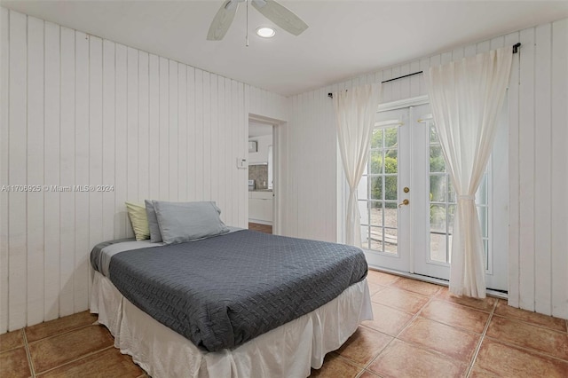 tiled bedroom featuring access to exterior, ceiling fan, and wooden walls