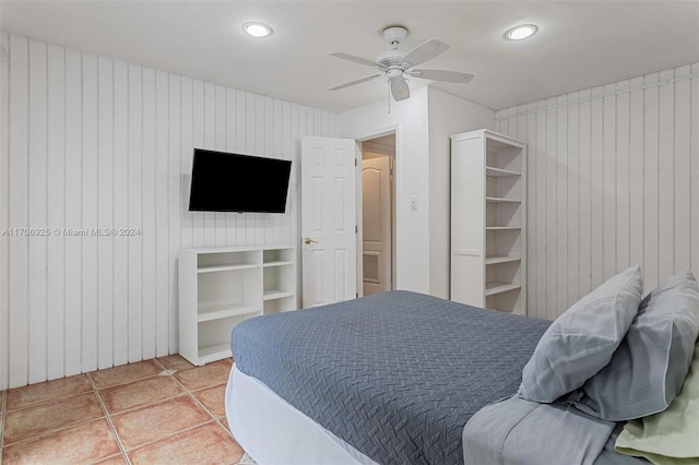 bedroom featuring tile patterned flooring, ceiling fan, and wood walls