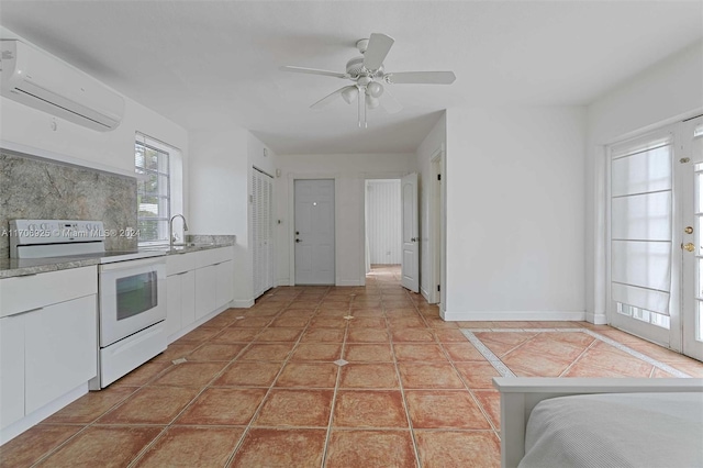 kitchen with ceiling fan, light tile patterned floors, an AC wall unit, white cabinets, and white electric range