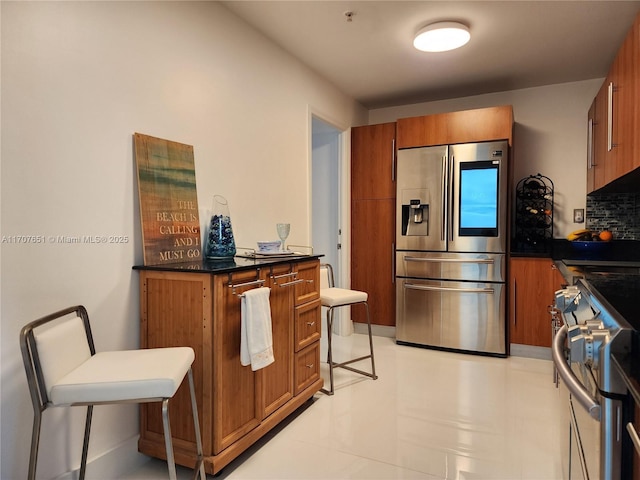 kitchen with range, brown cabinets, dark countertops, and stainless steel fridge