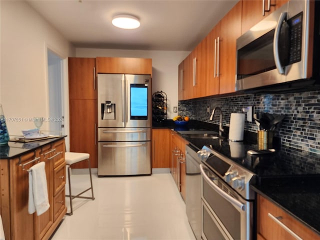 kitchen with decorative backsplash, stainless steel appliances, dark stone countertops, and sink