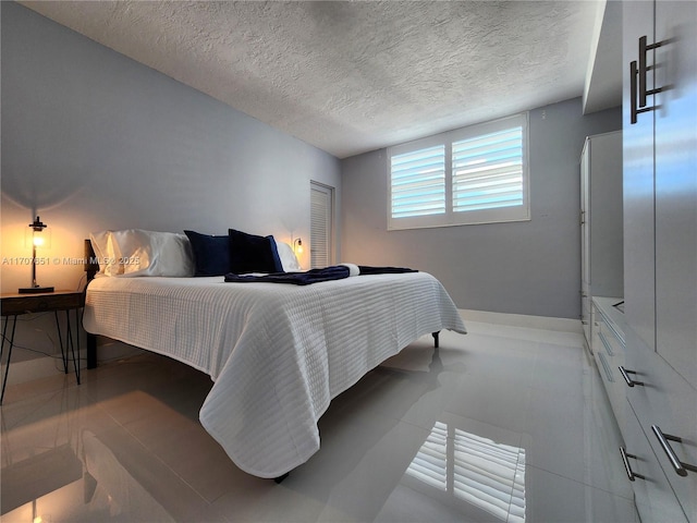 bedroom featuring tile patterned flooring, baseboards, and a textured ceiling