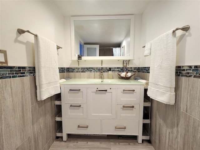 bathroom with tile walls, wainscoting, vanity, and wood finished floors