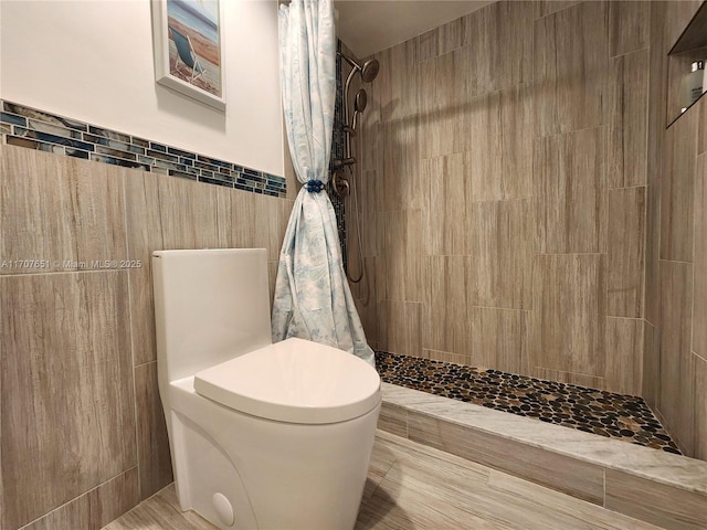 full bathroom featuring tiled shower and tile walls