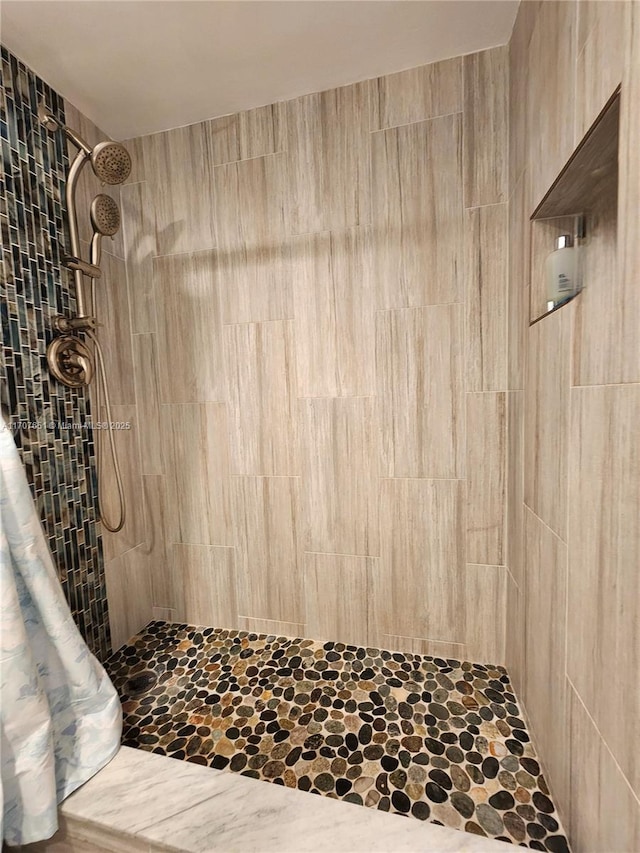 bathroom with tiled shower and stone finish flooring