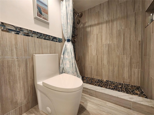 bathroom with toilet, tile walls, and curtained shower