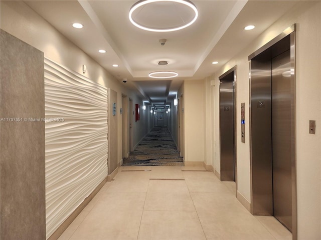 corridor with recessed lighting, a tray ceiling, light tile patterned floors, and elevator