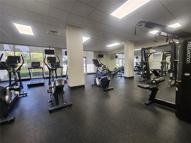 gym with visible vents, a paneled ceiling, and a healthy amount of sunlight