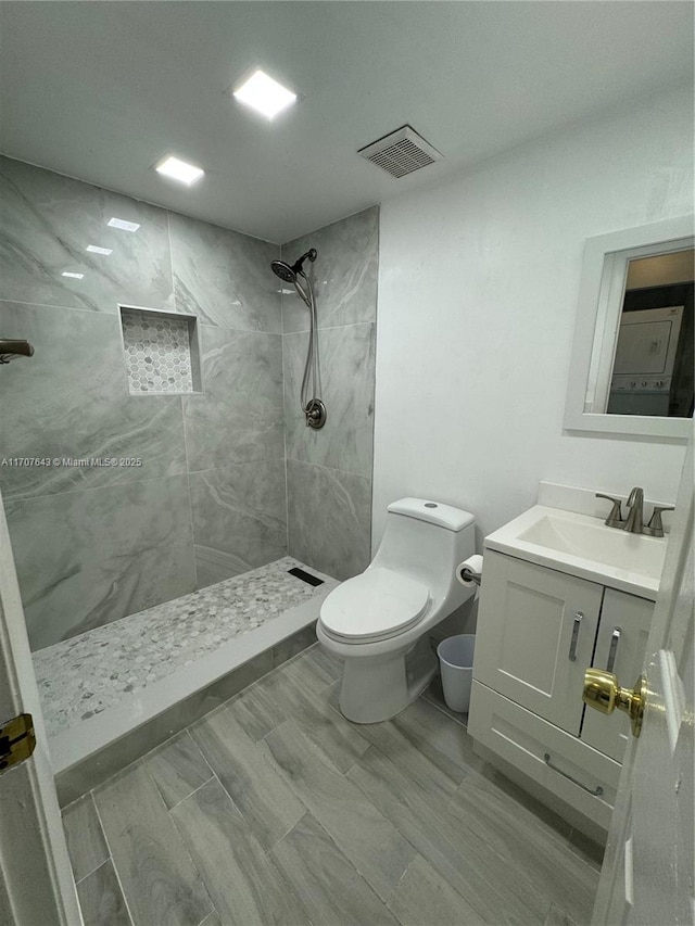 bathroom featuring tiled shower, vanity, and toilet