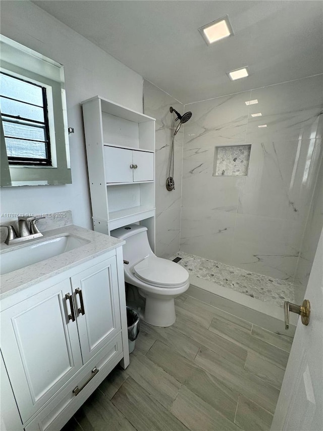 bathroom with vanity, toilet, and a tile shower