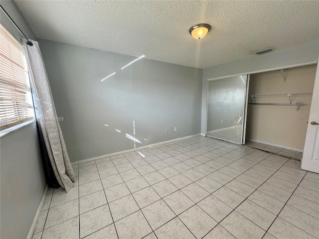 unfurnished bedroom featuring light tile patterned floors, a textured ceiling, and a closet