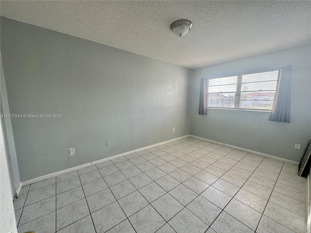 tiled empty room featuring a textured ceiling