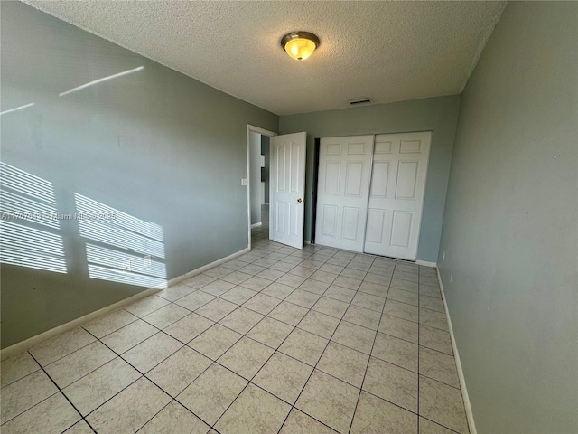 unfurnished bedroom featuring a closet, light tile patterned floors, and a textured ceiling