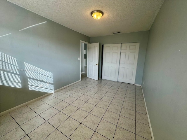 18250 Mediterranean Blvd Unit 8-15 15-8, Hialeah, FL 33015 - unfurnished bedroom featuring a textured ceiling, a closet, and light tile patterned flooring