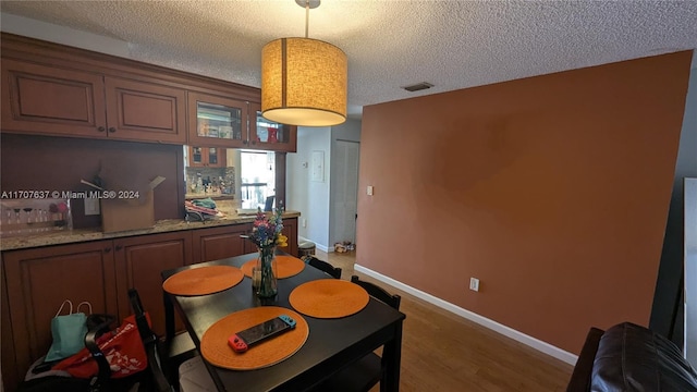 dining space featuring dark wood-type flooring and a textured ceiling