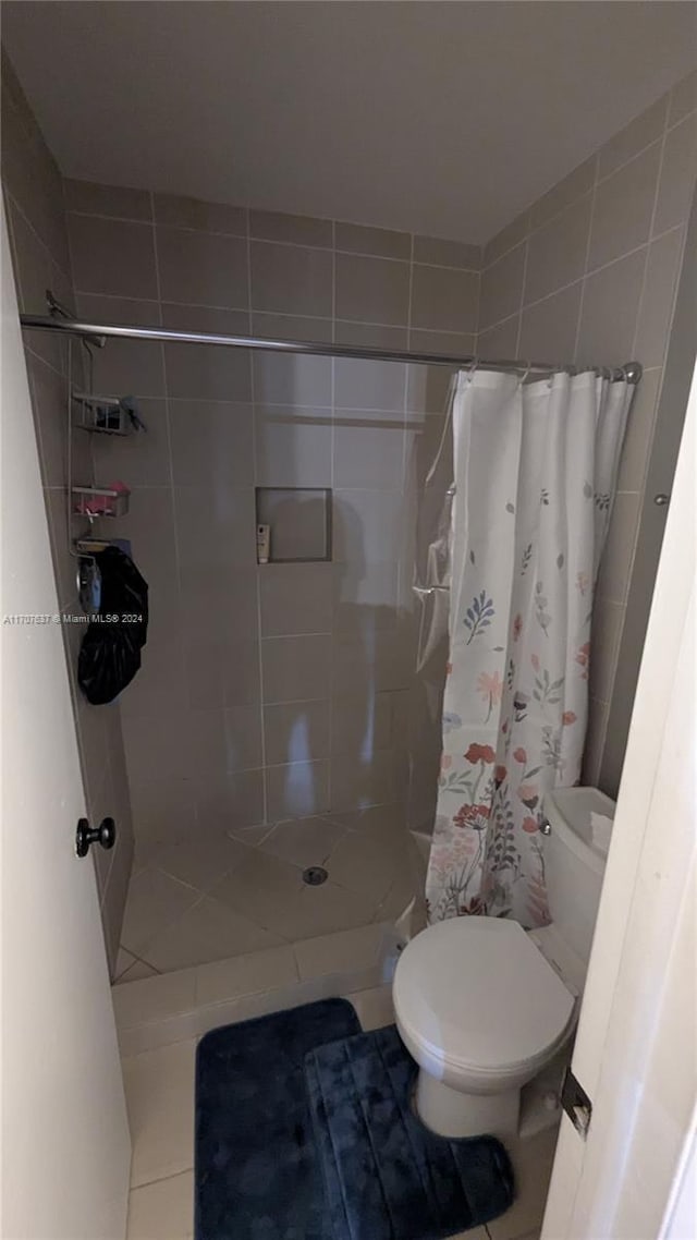 bathroom with a shower with shower curtain, tile patterned flooring, and toilet