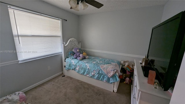 carpeted bedroom featuring ceiling fan and a textured ceiling