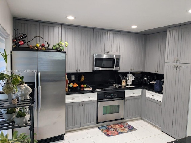 kitchen with gray cabinets, light tile patterned floors, and stainless steel appliances