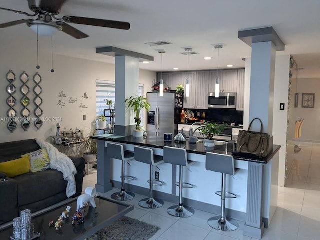 kitchen featuring kitchen peninsula, decorative backsplash, a kitchen bar, stainless steel appliances, and hanging light fixtures