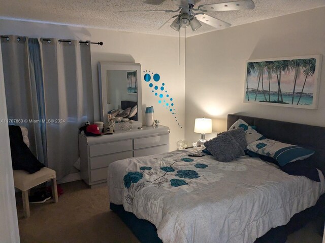 carpeted bedroom with ceiling fan and a textured ceiling