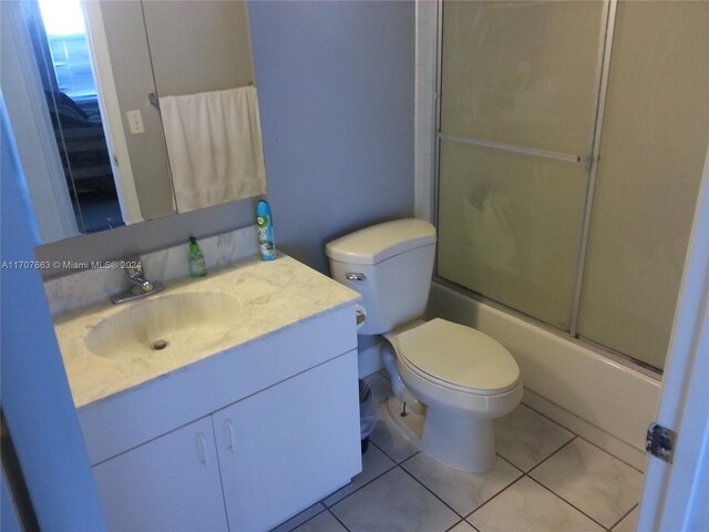 full bathroom with tile patterned floors, vanity, toilet, and bath / shower combo with glass door