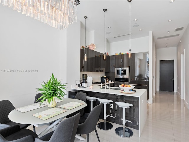 kitchen featuring kitchen peninsula, sink, light tile patterned floors, a notable chandelier, and dark brown cabinets