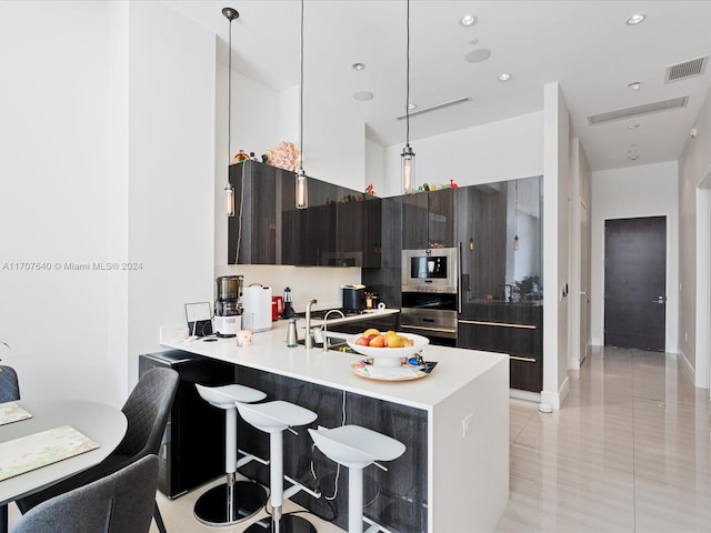 kitchen with a breakfast bar, kitchen peninsula, decorative light fixtures, light tile patterned flooring, and dark brown cabinetry