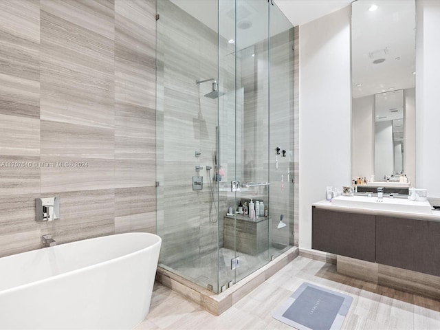 bathroom with plus walk in shower, vanity, tile walls, and tile patterned flooring