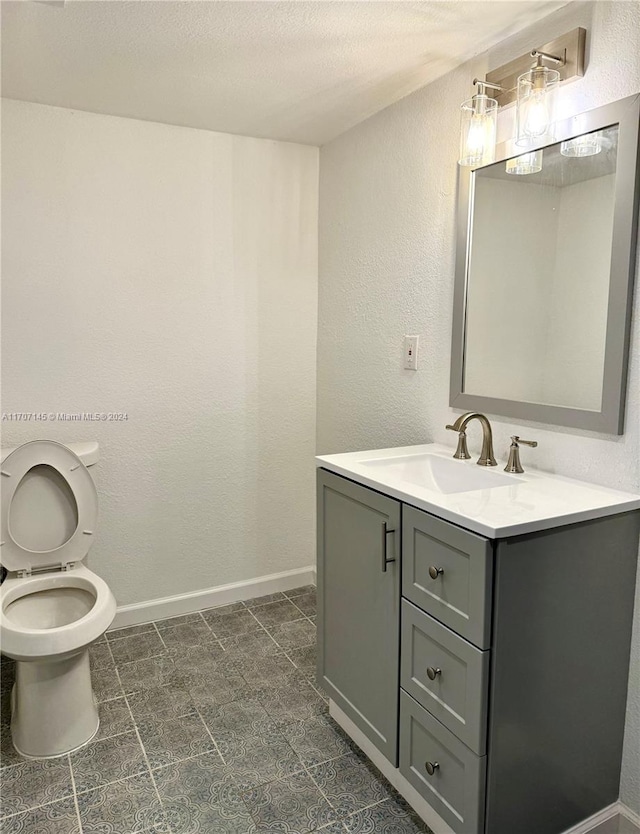 bathroom with vanity, a textured ceiling, and toilet